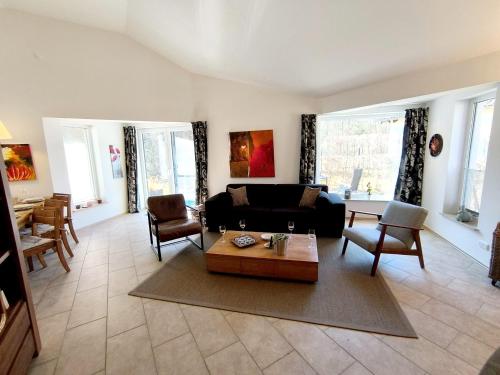 un soggiorno con un divano e un tavolo di Luxuriöses, familienfreundliches Ferienhaus ,,Amy,, mit Whirlpoolwanne, Kamin und Garten a Hinterhausen