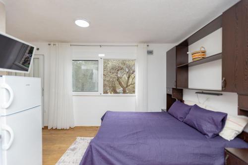 a bedroom with a purple bed and a refrigerator at Apartments Oliva in Utjeha
