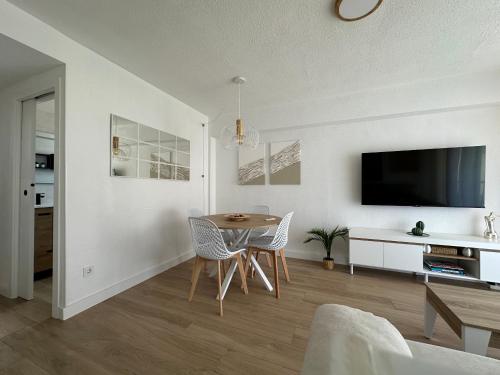 een woonkamer met een tafel en stoelen en een televisie bij SATORI Romantyczny azyl dla dwojga 150 m od plaży - apartament z balkonem i parkingiem, Playa de Gandia in Playa de Gandia