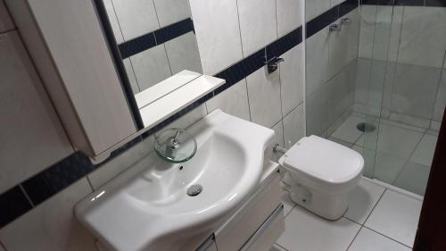 a bathroom with a sink and a toilet and a mirror at CASA DO BRAZ aptos e casa de temporada in Monte Verde