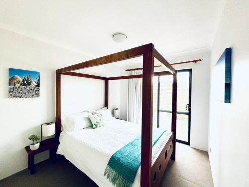 a bedroom with a canopy bed and a window at Troon Retreat! Golf, Wineries, beaches in Dunsborough