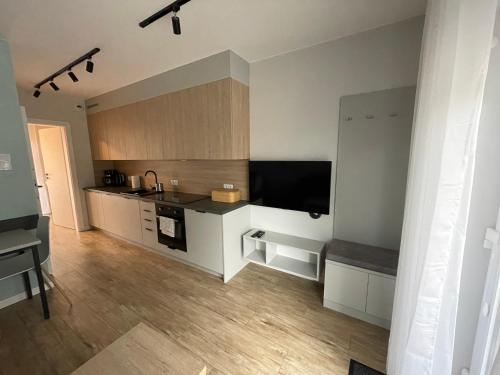 a kitchen with white cabinets and a flat screen tv at Przystanek Karpacz - ul Słowackiego 5A in Karpacz