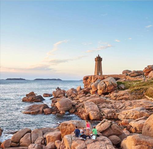 Un grupo de personas sentadas en las rocas cerca del océano. en Maison Yaudet à 50 M DE LA PLAGE, en Ploulech