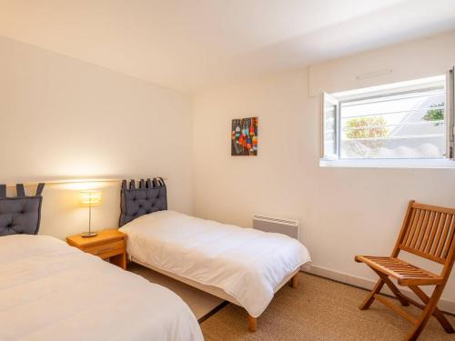 une chambre avec deux lits et une chaise et une fenêtre dans l'établissement Appartement 4 pièces à Carnac - Vue mer, terrasse, parking, accepte animaux - FR-1-477-72, à Carnac