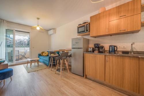 Il comprend une cuisine équipée d'un réfrigérateur et d'une table. dans l'établissement Magnifique 2 pièces, Clim, parking , wifi, à Beaulieu-sur-Mer
