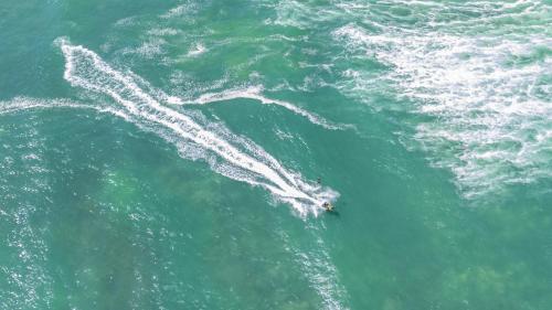 a person laying on a surfboard in the water at Pet & Family Friendly 3BR Coastal Escape Near Boat Ramp - Diyamba! in Encounter Bay