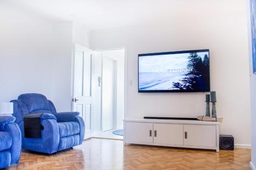 a living room with two chairs and a flat screen tv at Pet & Family Friendly 3BR Coastal Escape Near Boat Ramp - Diyamba! in Encounter Bay
