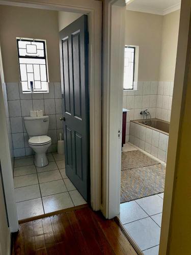 a bathroom with a toilet and a tub at Mount Road Suites in Port Elizabeth