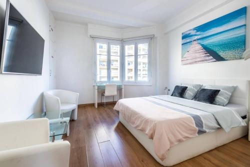 une chambre blanche avec un grand lit et une télévision à écran plat dans l'établissement Modern Sea View Apartment on Promenade des Anglais, à Nice