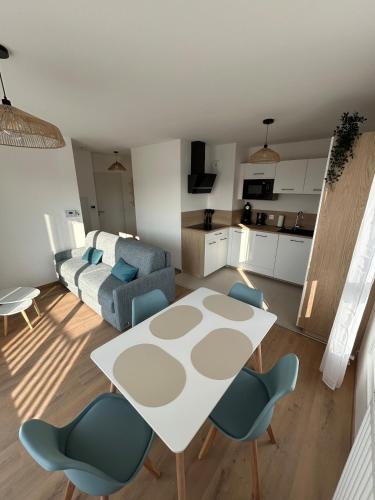 un salon avec une table et des chaises bleues dans l'établissement Le spot, à Camiers