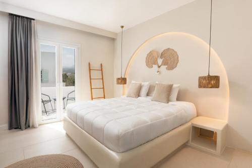 a white bedroom with a large bed and a balcony at Paridian Elegant Living in Parikia