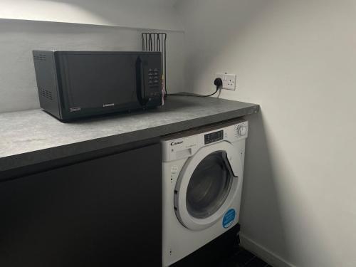 a microwave and a washing machine on a counter at ResiLets - The Monopoly Apartment - Large 4 bedroom in Bedlington