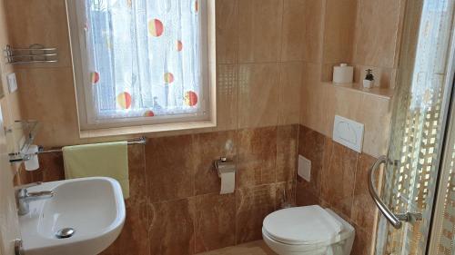 a bathroom with a toilet and a sink and a window at Csalogány Apartman Egerszalók in Egerszalók