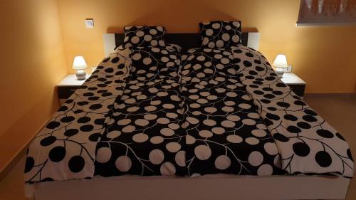 a bed with a black and white comforter at Csalogány Apartman Egerszalók in Egerszalók