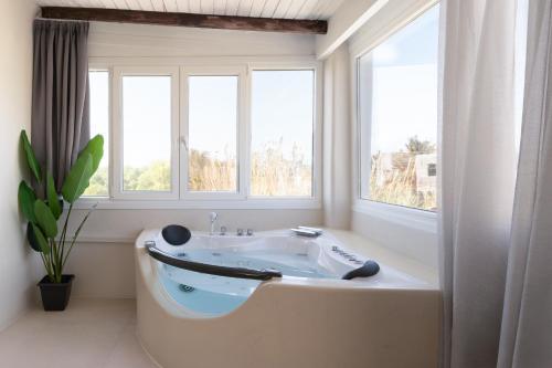 a bath tub in a bathroom with three windows at Paridian Elegant Living in Parikia