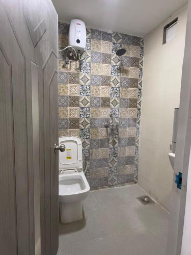 a bathroom with a toilet and a tiled wall at Simple Belle by Half Orangee with Swimming Pool ,Near to Beach -Clubs - Hill Top best for Corporate Bookings-Summer vacation!! in Vagator
