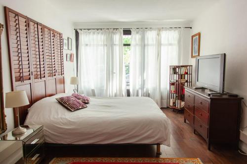 a bedroom with a bed and a dresser and a television at Maison Blanche in Nîmes