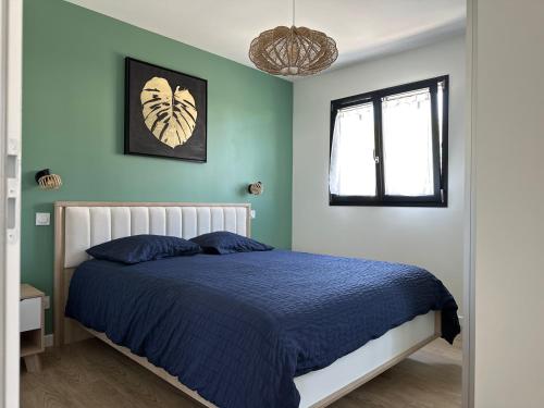une chambre avec un lit avec des draps bleus et une fenêtre dans l'établissement Ti case, à Gonneville-en-Auge