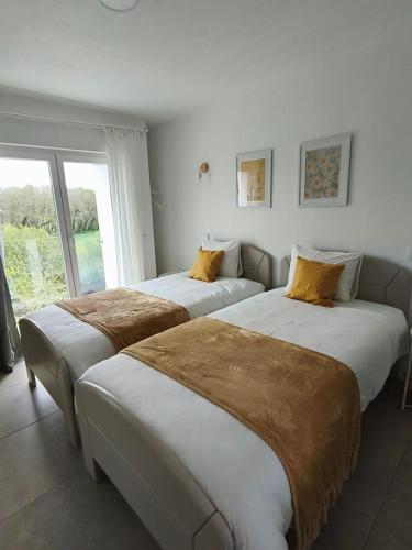 two beds in a room with a window at FlorAL in Aljezur