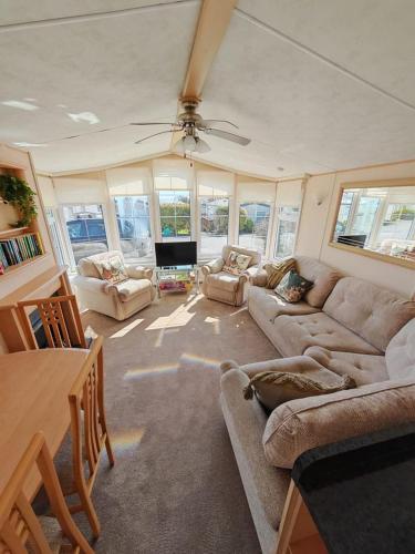a living room with couches and a ceiling fan at Sandy Feet in Amroth