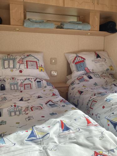 two beds in a room with white blankets and pillows at Sandy Feet in Amroth