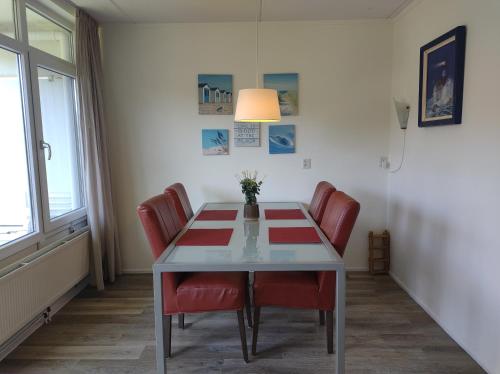 a dining room with a table and red chairs at VUURTOREN Bed by the Sea in Westkapelle