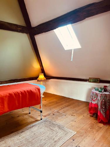 Cette chambre mansardée comprend un lit et une fenêtre. dans l'établissement Chambre La Coccinelle Verte, à Lyons-la-Forêt