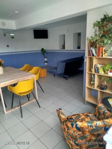 a living room with a table and yellow chairs at Albergue de São Bento in Caminha