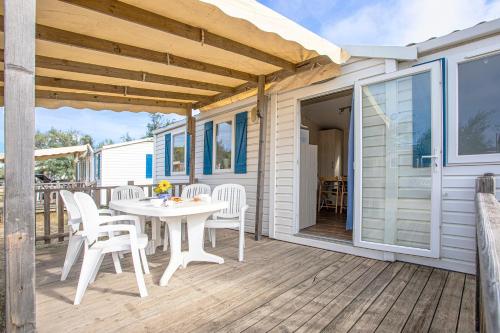 un patio con tavolo e sedie su un ponte di Camping Barberousse a Gruissan