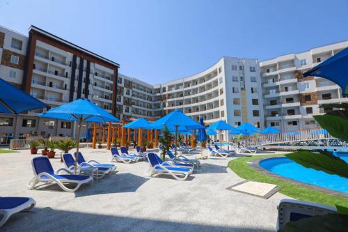 a group of chairs and blue umbrellas next to a pool at Tiba Golden Resort in Hurghada