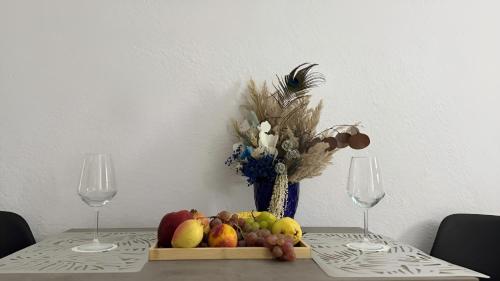 a table with a plate of fruit and two wine glasses at Angel's Studio Apartments in Tirana