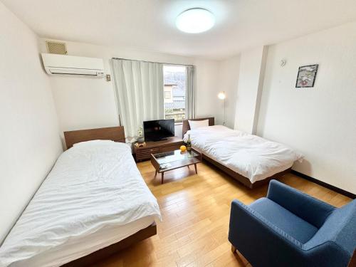 a hotel room with two beds and a blue chair at サンライズ in Nagano