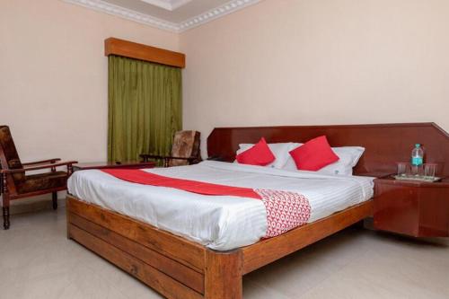 a bedroom with a large wooden bed with red pillows at Hotel Gurupriya in Kodaikānāl