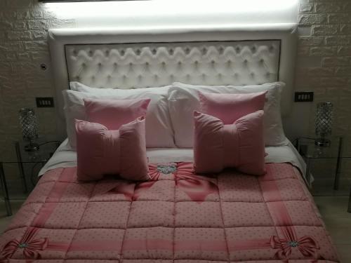 a white bed with pink pillows and a pink blanket at BB La Bella Addormentata e il Principe Calaf in Lucca