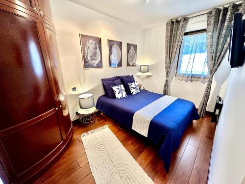 une chambre avec un lit bleu et une fenêtre dans l'établissement Cap sur l'Océan à 50m plages et piscine naturelle, à Saint-Gilles-Croix-de-Vie