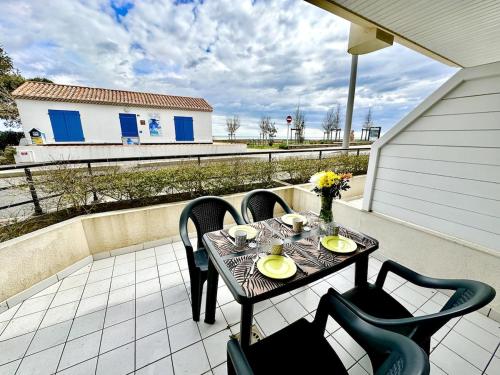 un patio avec une table et des chaises sur un balcon dans l'établissement Cap sur l'Océan à 50m plages et piscine naturelle, à Saint-Gilles-Croix-de-Vie