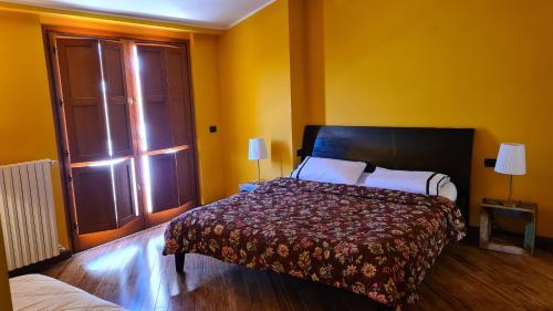 a bedroom with a bed in a yellow room at Villa gli Ulivi - Bariloche Lake & Mountain View in Perledo