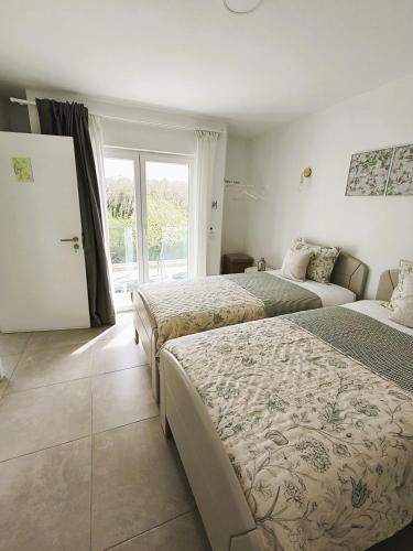 a bedroom with two beds and a large window at FlorAL in Aljezur