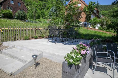 a patio with chairs and a table and flowers at Ferienwohnung Bergblick O1 in Osterode
