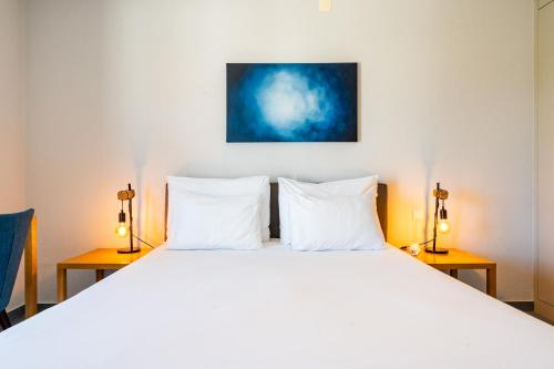 a bedroom with a large white bed with two lamps at Agua d'Alma Hotel in Foz do Arelho