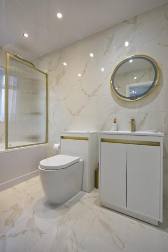 a white bathroom with a toilet and a mirror at Luxury Harborne Home, Perfect for Contractors & Families 5 Mins from QE & Uni in Birmingham