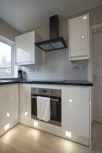 a kitchen with white cabinets and an oven with a towel at Luxury Harborne Home, Perfect for Contractors & Families 5 Mins from QE & Uni in Birmingham