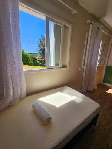 ein Bett in einem Zimmer mit Fenster in der Unterkunft Melhor cervejaria do Brasil e a Serra te esperam! in Orleans