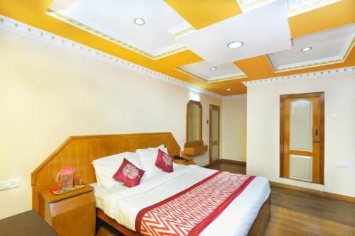 a bedroom with a large bed with red pillows at Hotel Gurupriya in Kodaikānāl