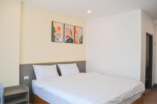 a bedroom with a white bed with three pictures on the wall at Apollo Vientiane Hotel in Vientiane
