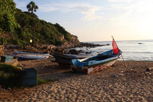 a group of boats on a beach near the water at Clara's Beach Inn in Trincomalee
