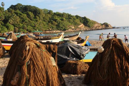 a group of boats on a beach with people on the shore at Clara's Beach Inn in Trincomalee