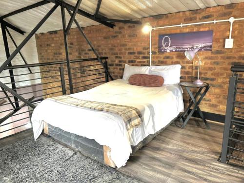 a bed in a room with a brick wall at Craftsmenship Loft in Johannesburg