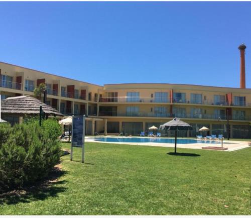 a large building with a swimming pool and umbrellas at Boca do Rio Arade in Estômbar