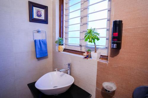 a bathroom with a toilet and a window with plants at Woodburry Mansion, Cozy Nainital Homestay in Nainital